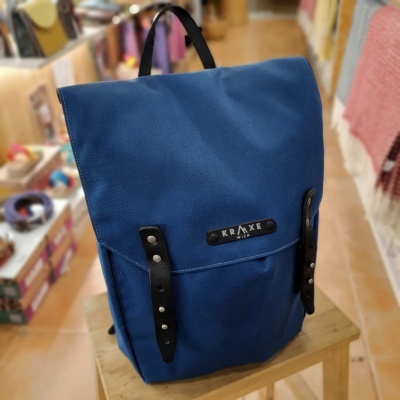 Mochila azul com detalhes em couro preto numa sala