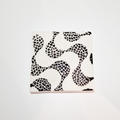 Peça quadrada em cerâmica branca com padrão abstrato preto.