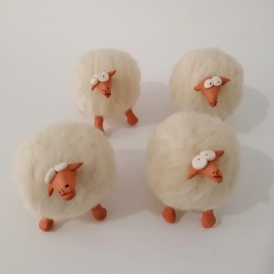 Quatro figuras decorativas de ovelhas felpudas brancas com cabeças e patas castanhas