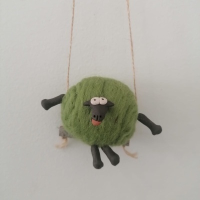 Decoração de ovelha verde felpuda pendurada na parede.