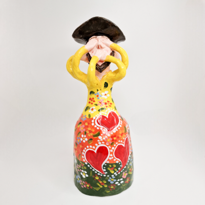 Estatueta cerâmica pintada com vestido amarelo, corações vermelhos e chapéu castanho