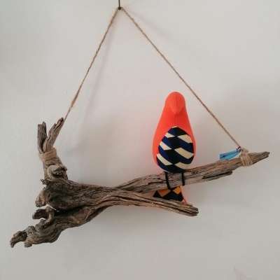 Decoração de parede com pássaro de tecido laranja e galho rústico suspenso por corda