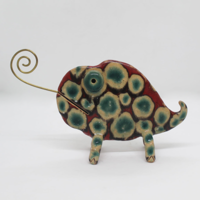Escultura de peixe em cerâmica decorada com padrão bolhas verdes e bege com rabo em espiral