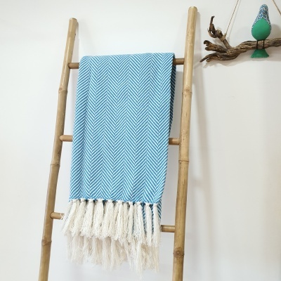 Manta azul com padrão espinha de peixe pendurada em escada de bambu