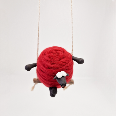 Pêndulo decorativo de ovelha vermelha sentada num baloiço de madeira
