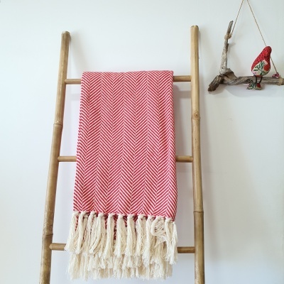 Manta vermelha com padrão espinha de peixe pendurada em escada de bambu