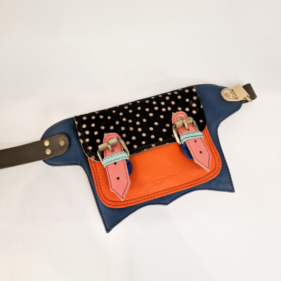 Bolsa cinto azul com bolso laranja, aba preta com bolinhas, detalhes cor-de-rosa e etiqueta SATCHI