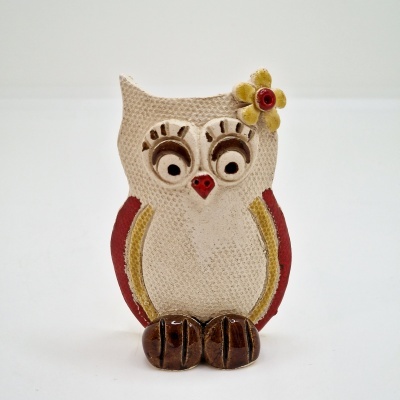 Figura de coruja decorativa em cerâmica com flor amarela na cabeça.