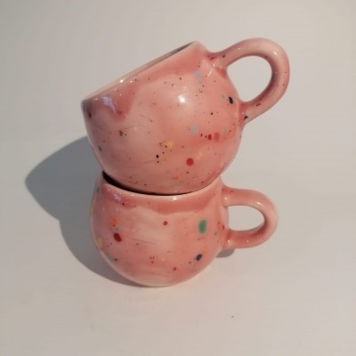 Duas chávenas de cerâmica cor de rosa com manchas coloridas empilhadas