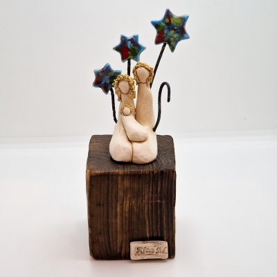 Escultura de família em cerâmica bege com base de madeira escura e estrelas coloridas em arames pretos