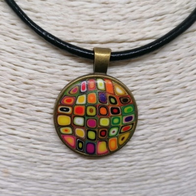 Colar com pendente redondo colorido e cordão preto sobre fundo bege texturizado