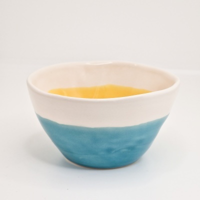 Taça de cerâmica com interior amarelo e exterior azul turquesa.