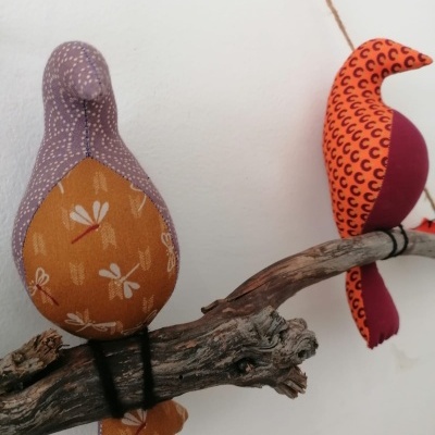 Dois pássaros decorativos de tecido colorido sobre ramo seco
