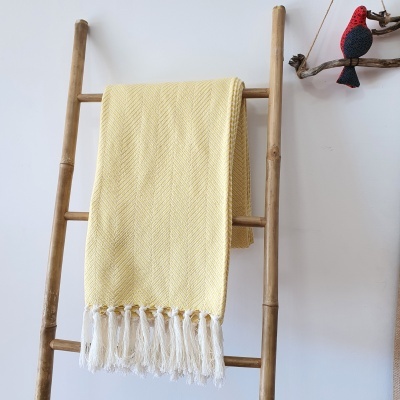 Manta amarela com franjas pendurada numa escada de madeira