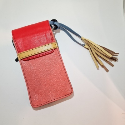 Bolsa de mão vermelha e coral com faixa bege e tassel numa superfície branca