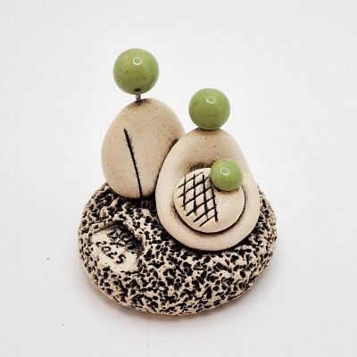 Escultura decorativa cerâmica com formas ovais bege, esferas verdes e base texturada.