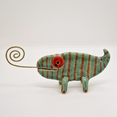 Escultura de camaleão verde com riscas castanhas e mola dourada na boca