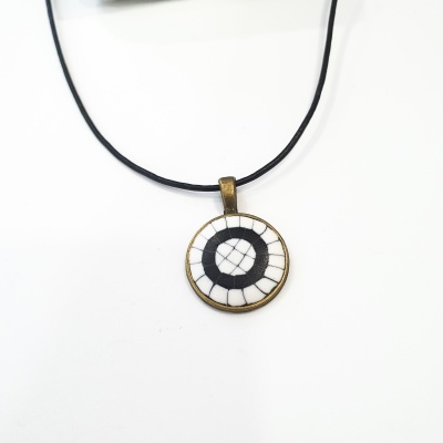 colar com pendente redondo em metal dourado com padrão circular preto e branco