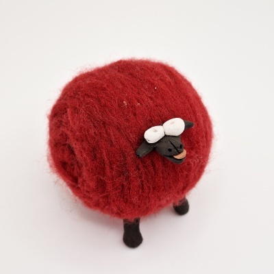 Figura de ovelha decorativa com corpo vermelho felpudo e cabeça preta
