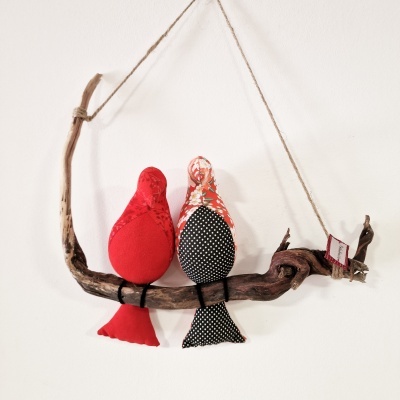 Dois pássaros decorativos de tecido pendurados num ramo de madeira