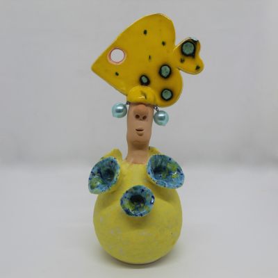Figura em cerâmica com vestido amarelo e chapéu decorado a amarelo com pontos pretos e azuis