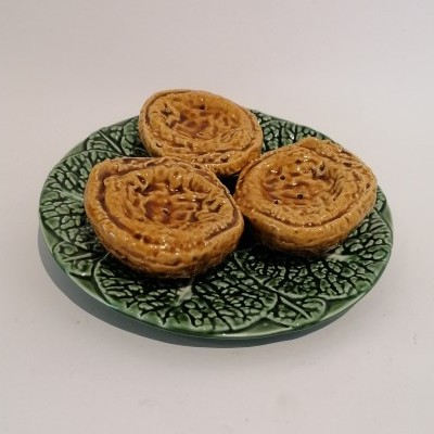 Três pastéis de nata num prato verde com padrão de folhas