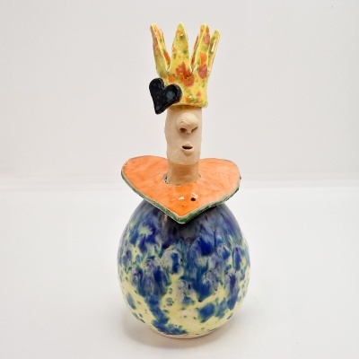 Escultura de cerâmica colorida de figura humana com coroa, coração preto e camisa laranja