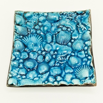 Prato quadrado de cerâmica azul com padrão de conchas marinhas em relevo