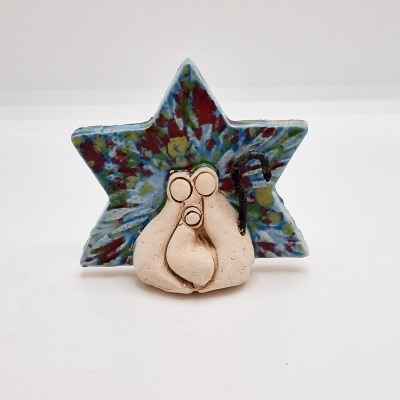 Figura decorativa de barro com três personagens e uma estrela colorida