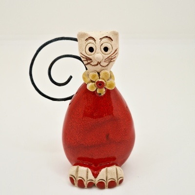 Figura decorativa em forma de gato vermelho com cabeça e patas creme e rabo espiralado.