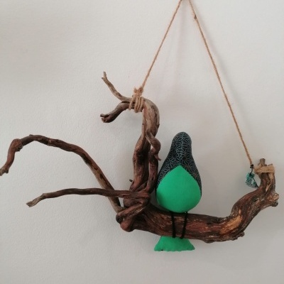 Decoração de parede com galho de madeira e pássaro de tecido verde e preto