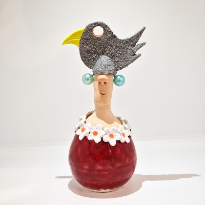 Boneco decorativo vermelho com pássaro preto na cabeça