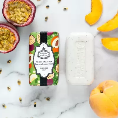 Sabonete pêssego e maracujá em embalagem colorida com frutas e sabonete branco ao lado, rodeados por frutas frescas
