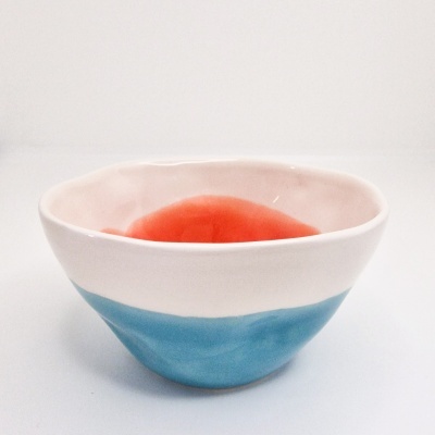Tigela cerâmica branca, vermelha e azul sobre superfície branca