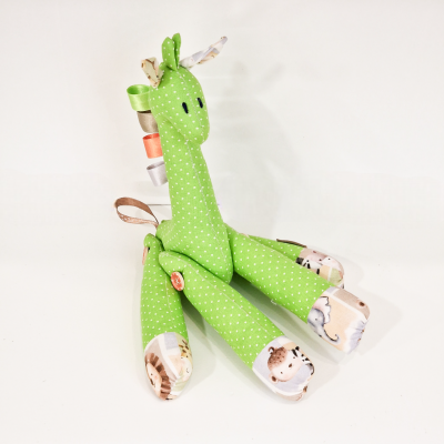 Pelúcia de girafa verde com pontos brancos e detalhes coloridos