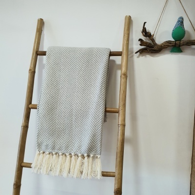 Escada decorativa de madeira com mantinha cinzenta e franjas pendurada