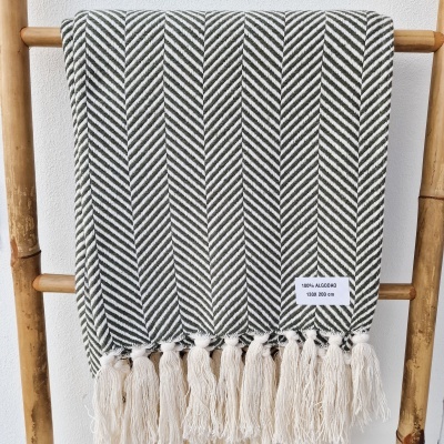 Manta de algodão verde escuro e branca pendurada numa escada de madeira