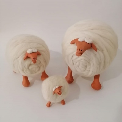 Três ovelhas decorativas de lã branca com cabeça e pernas castanho-alaranjadas.