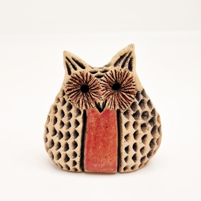 Figura decorativa de coruja em cerâmica com textura e cores bege, preta e vermelha.