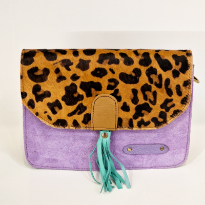 Mala pequena em camurça lilás com aba com padrão animal print e pendente azul turquesa.