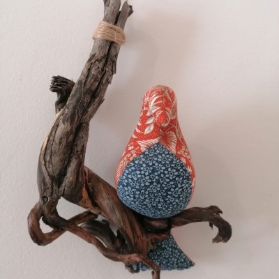 Pássaro decorativo de tecido vermelho e azul pendurado em galho de madeira