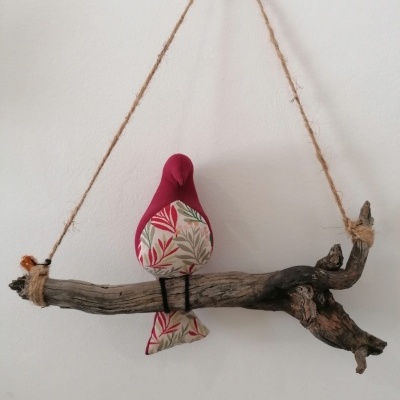 Decoração de parede com ramo de madeira e pássaro de tecido pendurados