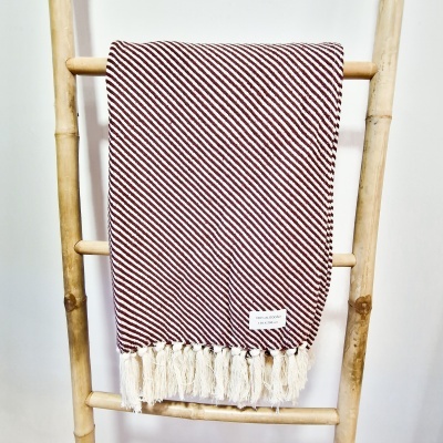 Manta riscada em vermelho e branco com franjas pendurada numa escada de madeira