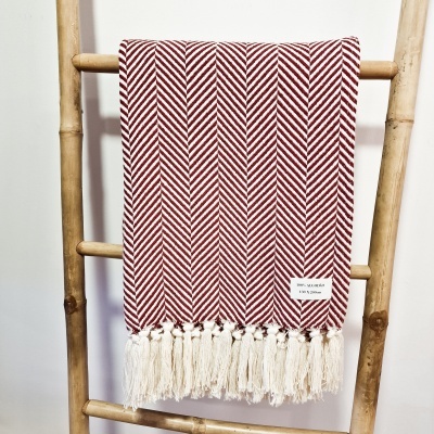 Manta vermelha e branca com padrão de espinha de peixe pendurada numa escada de madeira