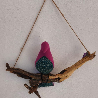 Pássaro decorativo de tecido rosa e verde sobre madeira pendurado na parede