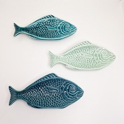 Três pratos cerâmicos em forma de peixe com textura de escamas em azul escuro, azul claro e verde claro