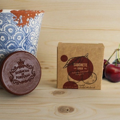 Sabonete redondo castanho e embalagem quadrada de sabonete em madeira clara com pote decorativo e cerejas