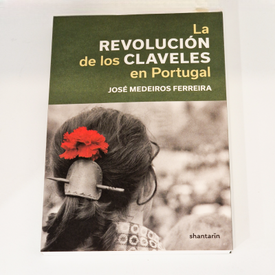 Capa do livro 'La Revolución de los Claveles en Portugal' com fotografia de pessoa com cravo vermelho no cabelo.