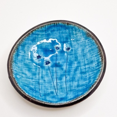 Prato redondo azul com decoração de flores e borda castanha