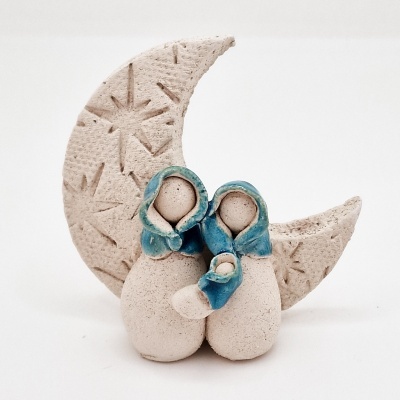 Estatueta decorativa de família com lua crescente em pedra e capuzes azuis.